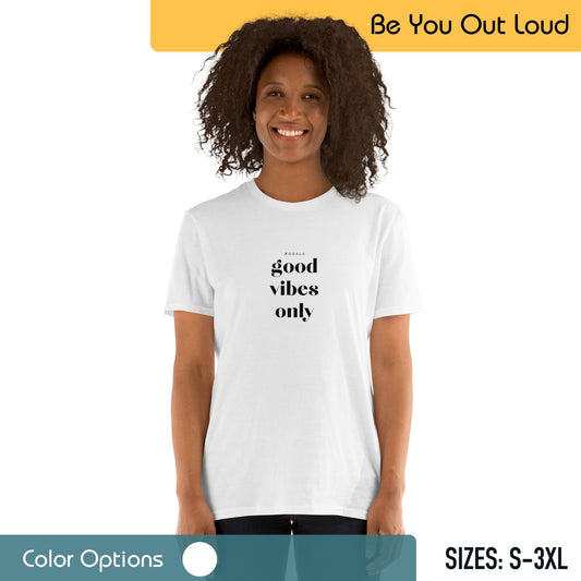 A smiling woman wearing a white T-shirt with the text "good vibes only" on it, standing in front of a background that includes the text "Be You Out Loud" and a color options palette, with available sizes from S to 3XL indicated.