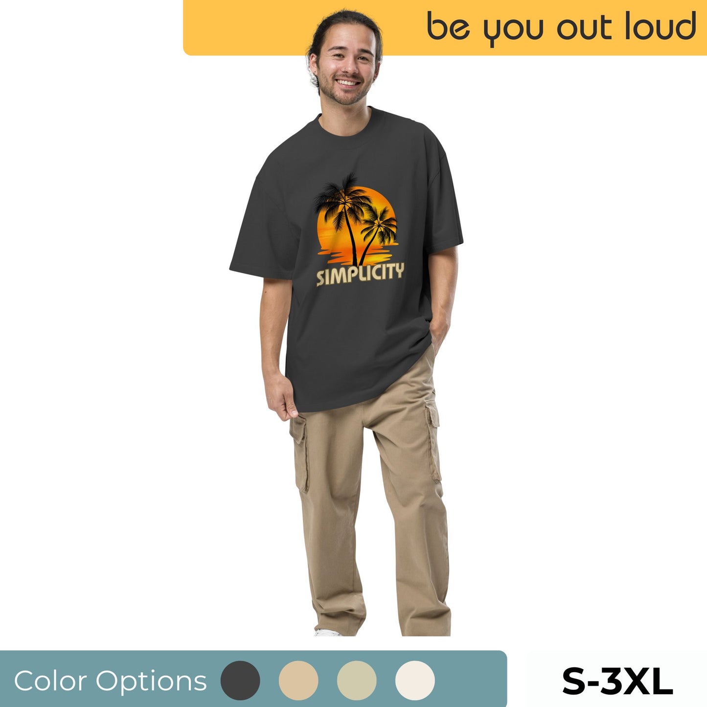 Alt Text: Smiling man wearing "Be You Out Loud" Men's Oversized Tee in black with a vibrant "Simplicity" palm tree graphic, sizes S-3XL, with color options available, showcasing a relaxed and timeless style.