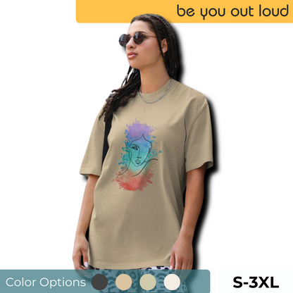 Stylish woman in a Be You Out Loud's olive oversized tee featuring a vivid watercolor-style artistic face design, available in sizes S to 3XL, highlighting self-expression and artistic flair.