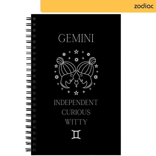 A notepad with a black background features the zodiac sign Gemini, illustrated with a symbolic twin profile design adorned with stars. Below the artwork, the words 'INDEPENDENT CURIOUS WITTY' describe the attributes associated with the sign, followed by the Gemini astrological symbol.