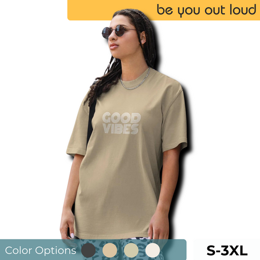 A stylish woman models the Women's Good Vibes Oversized Tee in a neutral tone, featuring bold 'GOOD VIBES' text, paired with chic sunglasses. Shirt available in S-3XL, with color swatches below.