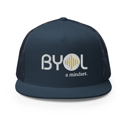 Navy blue 5-panel trucker hat with "BYOL a mindset" embroidered on the front in white and yellow, displayed against a clean background. Available in various colors: gray, maroon, white and blue, blue, and teal.