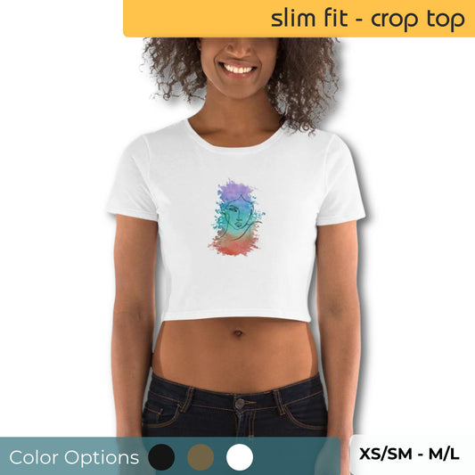 Cheerful woman sporting a Be You Out Loud Slim Fit White Crop Top with a colorful watercolor face design, paired with classic dark jeans, available in XS/SM to M/L.