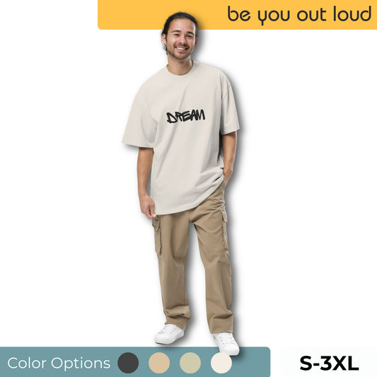 Cheerful man wearing a trendy off-white 'DREAM' graphic tee with coordinating khaki cargo pants, complete with white sneakers. Outfit comes in color choices of black, grey, teal, and khaki, available in sizes S through 3XL