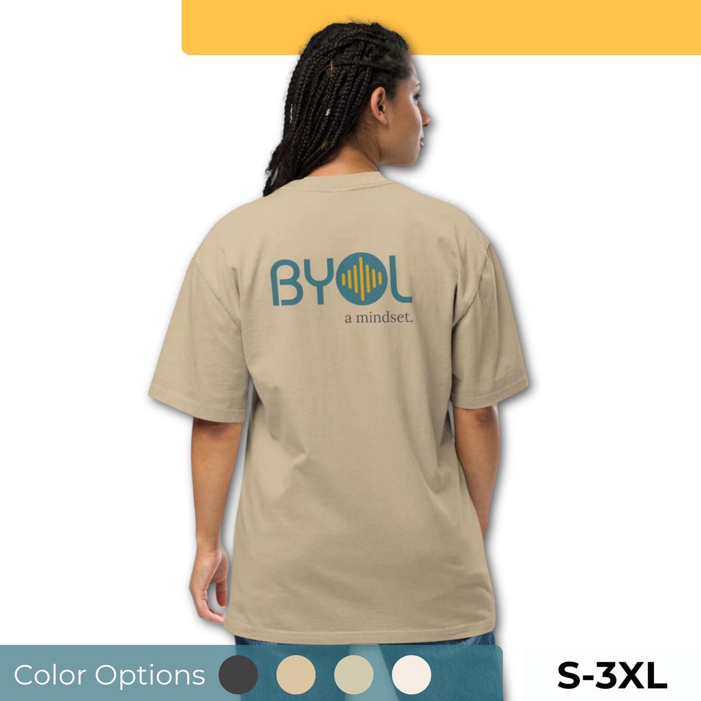 A young woman with long braids wearing a faded khaki "BYOL: a mindset" T-shirt, viewed from the back. The T-shirt features the "BYOL" logo in teal and yellow on the back and is available in multiple colors (dark gray, beige, light blue, white, plus more) and sizes (S-3XL). The "be you out loud" logo is displayed at the top.