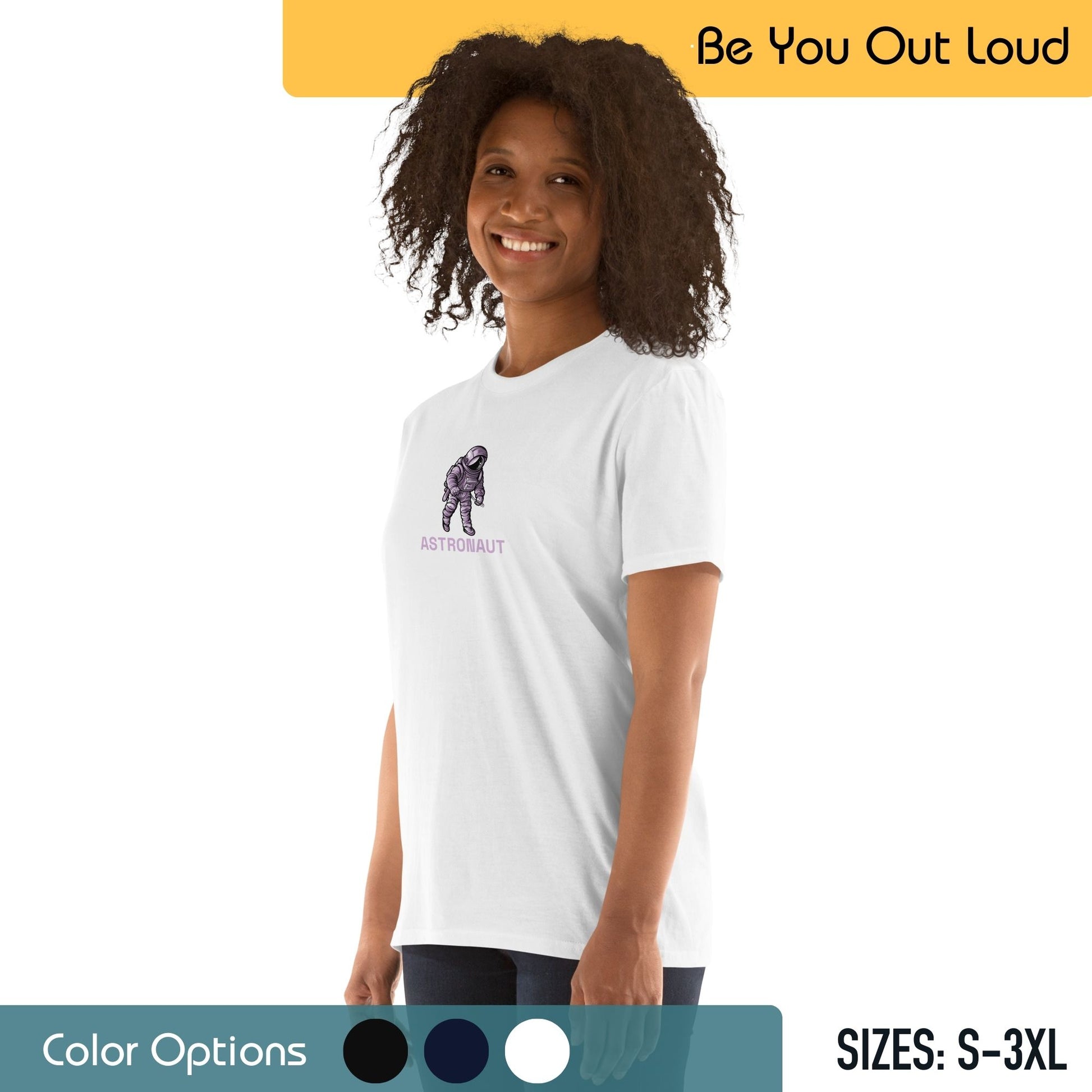 A woman with curly hair smiling and wearing a white T-shirt with a small illustration of an astronaut and the word "ASTRONAUT" below it. The background includes the slogan "Be You Out Loud," a color options palette, and available T-shirt sizes from S to 3XL.