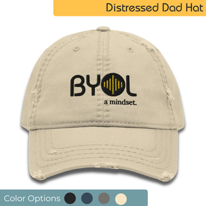 Khaki distressed dad hat with "BYOL a mindset" embroidered on the front in black and yellow, displayed against a clean background. Available in various colors: black, navy blue, gray, green, and beige.