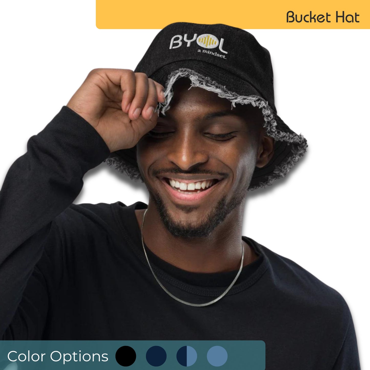 Man wearing a black bucket hat with frayed edges and "BYOL a mindset" embroidered on the front in white and yellow, smiling and posing against a clean background. Available in various colors: black, dark blue, light blue, and teal.