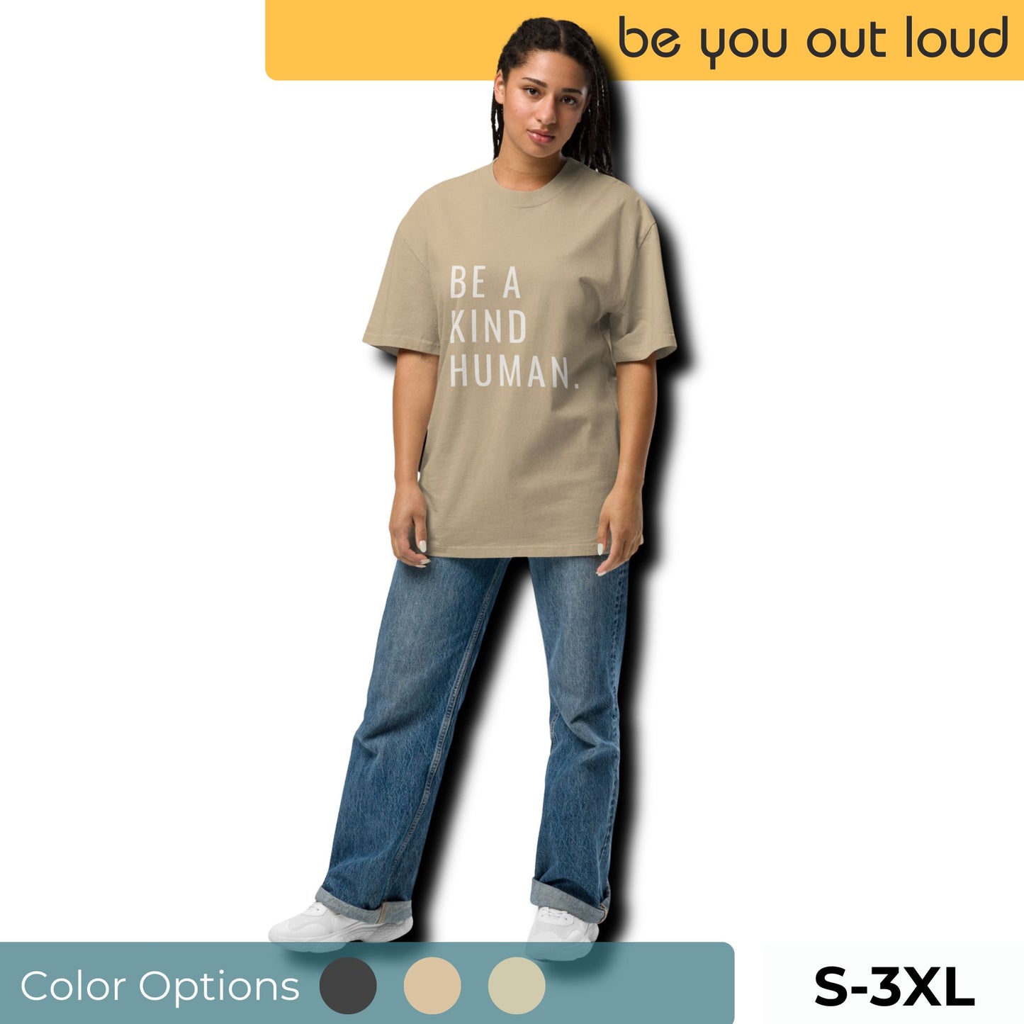 Model wearing a beige oversized T-shirt with 'BE A KIND HUMAN.' slogan in bold letters, paired with blue jeans and white sneakers, showcasing color options and sizes S to 3XL for inclusive fashion line 'be you out loud'.