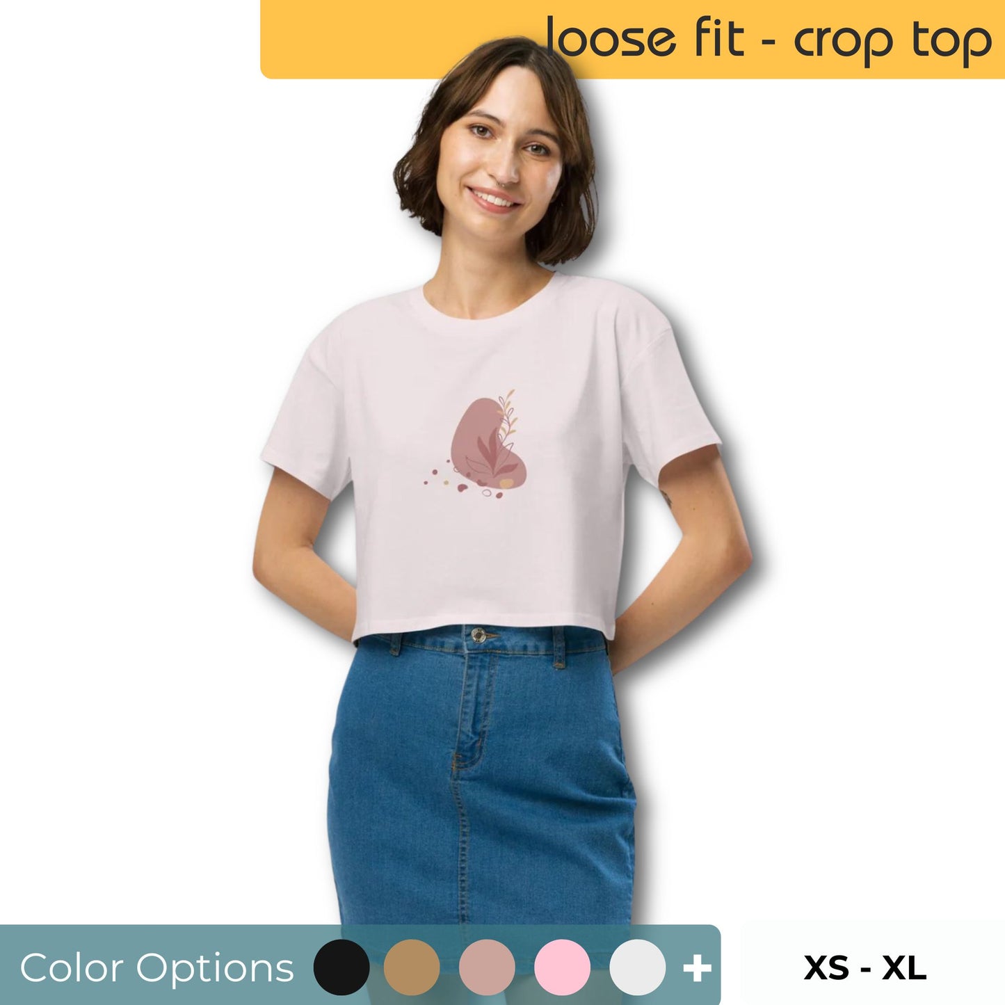 Woman wearing a ecru colored loose-fit crop top with a subtle muted graphic design, showcasing comfortable and authentic fashion by BYOL. Showing color and size options