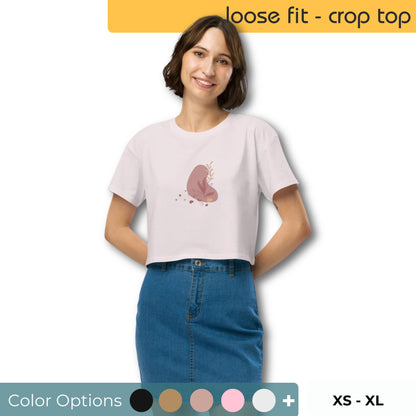 Woman wearing a ecru colored loose-fit crop top with a subtle muted graphic design, showcasing comfortable and authentic fashion by BYOL. Showing color and size options