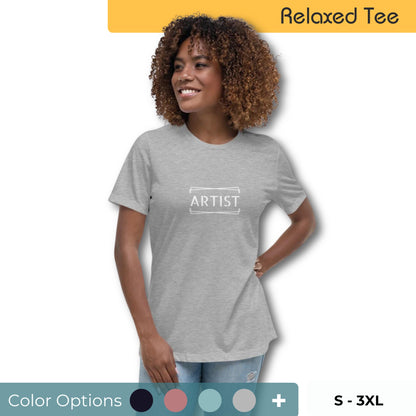 Confident woman with curly hair wearing a light grey relaxed tee with 'ARTIST' printed in bold letters within a simple frame, available in multiple colors, sizes X-3XL