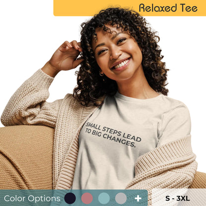 Woman wearing an off-white relaxed tee with "Small Steps Lead to Big Changes" printed, available in various colors and sizes from S-3XL.