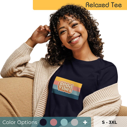 Smiling woman with curly hair wearing a navy blue relaxed tee with a 'good vibes' graphic in retro color stripes, paired with a beige knitted cardigan, available in multiple colors, sizes S-3XL