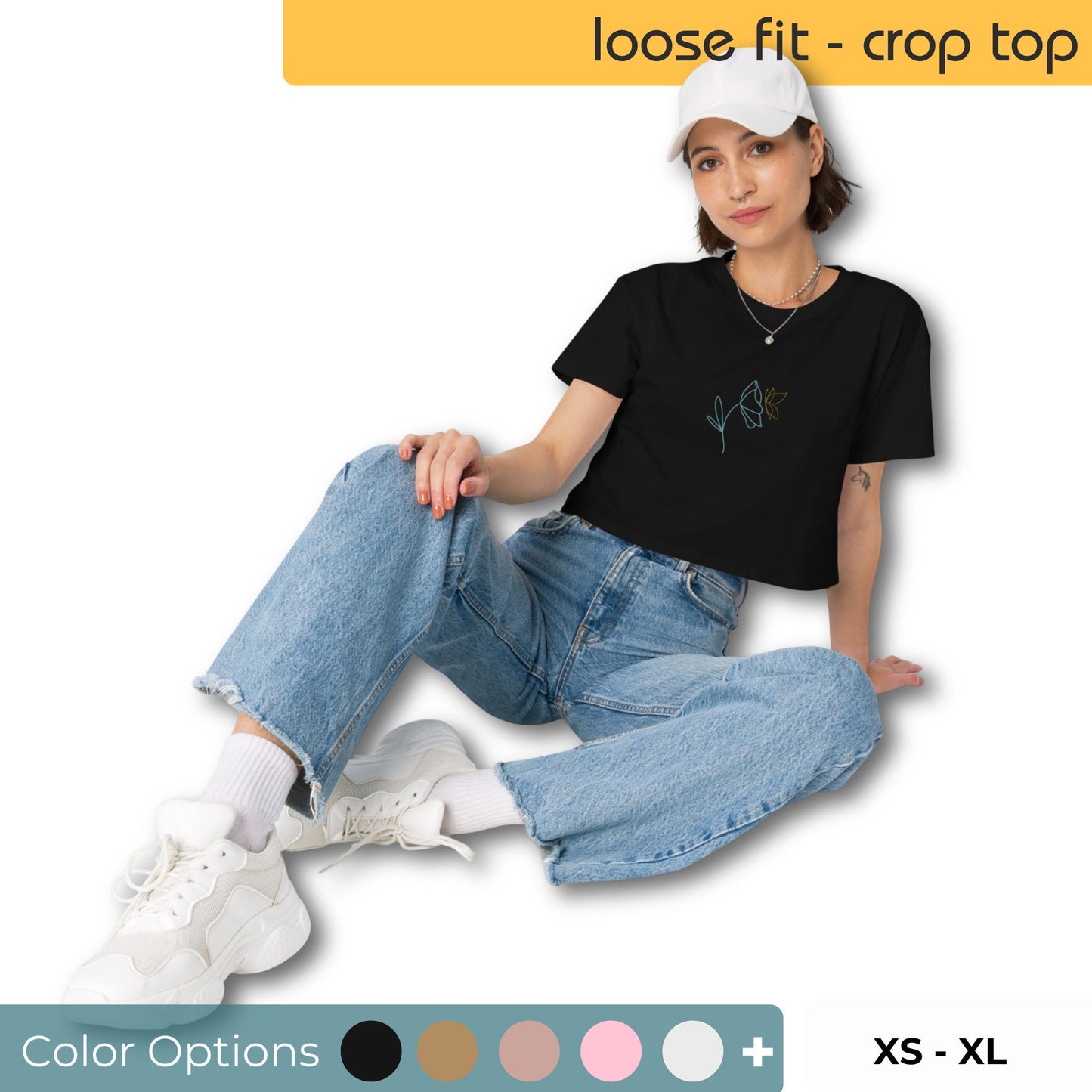 Woman wearing a black loose-fit crop top with a minimalist floral graphic design, representing comfortable and authentic fashion by BYOL. Showing color and size options