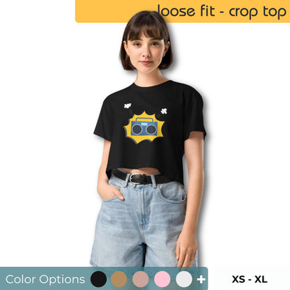 Young woman sporting a black loose-fit crop top with a vintage camera graphic and whimsical details, available from XS to XL.