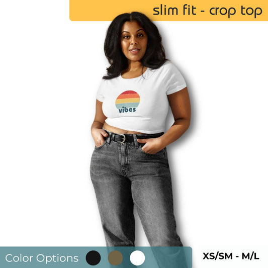 Confident woman wearing a white slim fit crop top with a colorful 'vibes' logo, paired with grey jeans, highlighting size options XS/SM to M/L and available color choices.