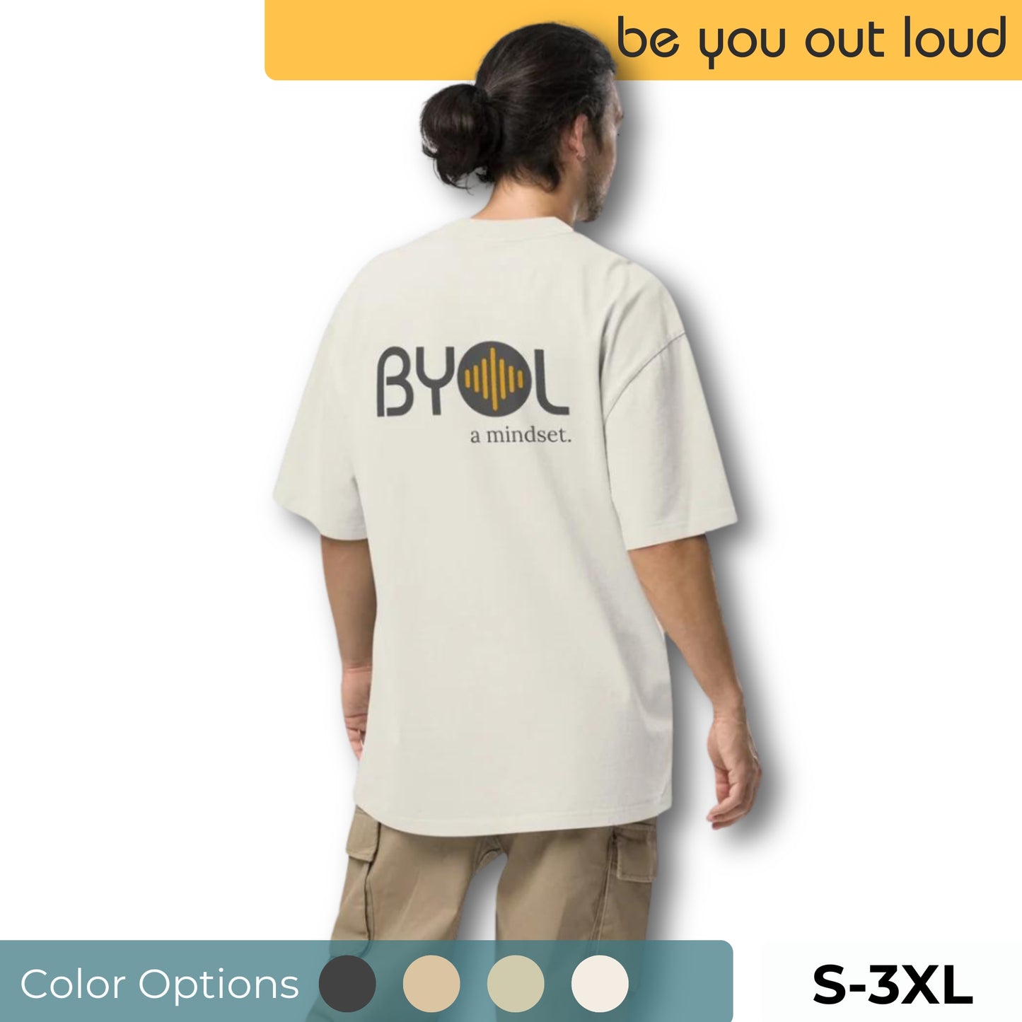 A young man with long hair in a ponytail wearing a eucalyptus "BYOL: a mindset" T-shirt, viewed from the back. The T-shirt features the "BYOL" logo on the back and is available in multiple colors (dark gray, beige, light blue) and sizes (S-3XL). The "be you out loud" logo is displayed at the top.