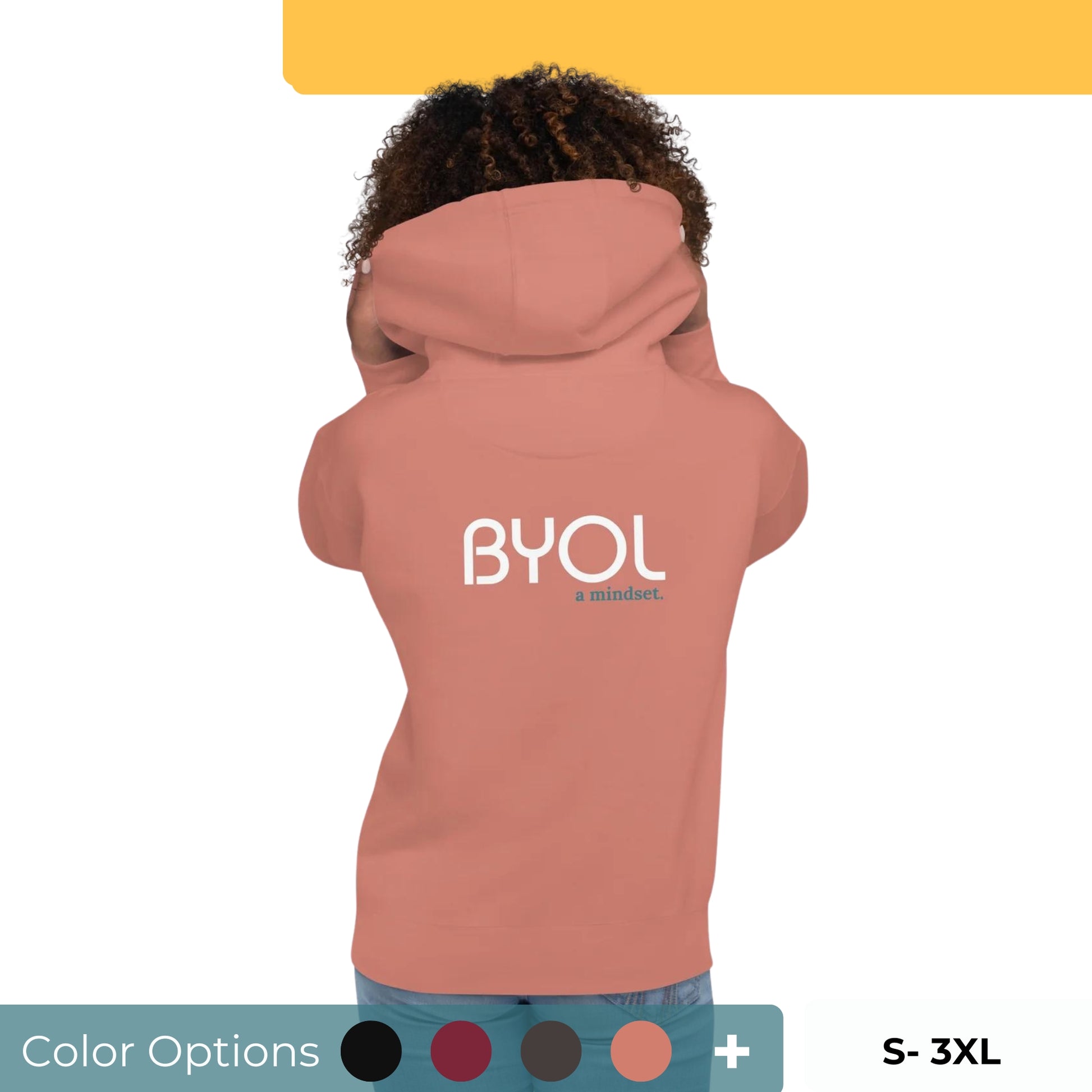 Back view of a woman wearing a pink BYOL mindset hoodie with color options in black, maroon, dark gray, and light pink, available in sizes S to 3XL.