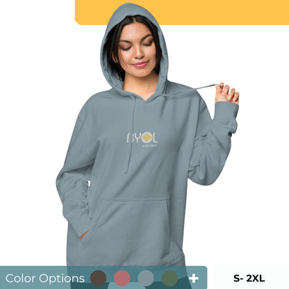 Woman wearing a pigmented blue BYOL mindset hoodie with color options in brown, pink, gray, and green, available in sizes S to 2XL.