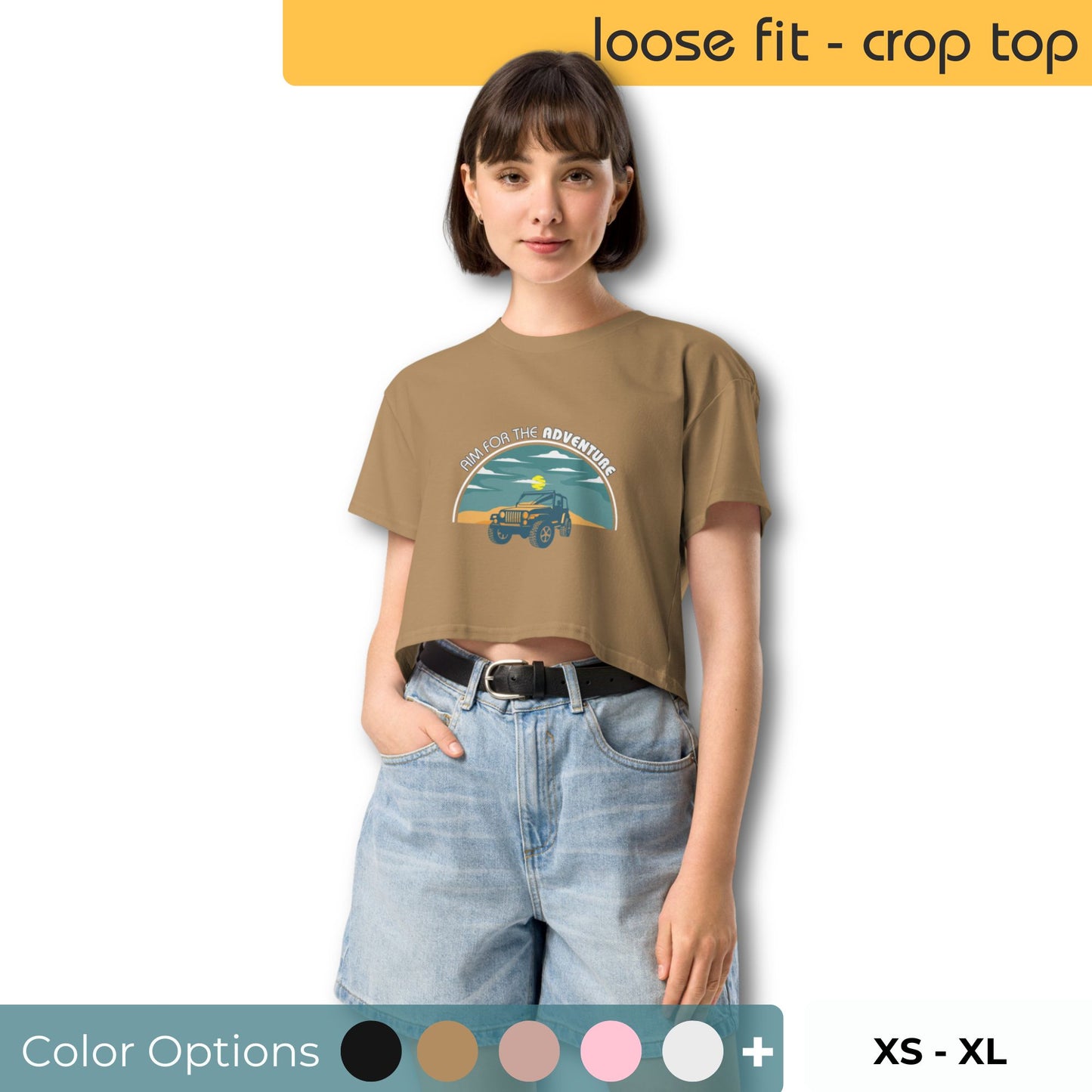 Young woman with a relaxed stance wearing an olive green crop top featuring a 'Aim for the Adventure' graphic with an off-road vehicle, paired with light-washed denim shorts, alongside color options and available sizes XS to XL.