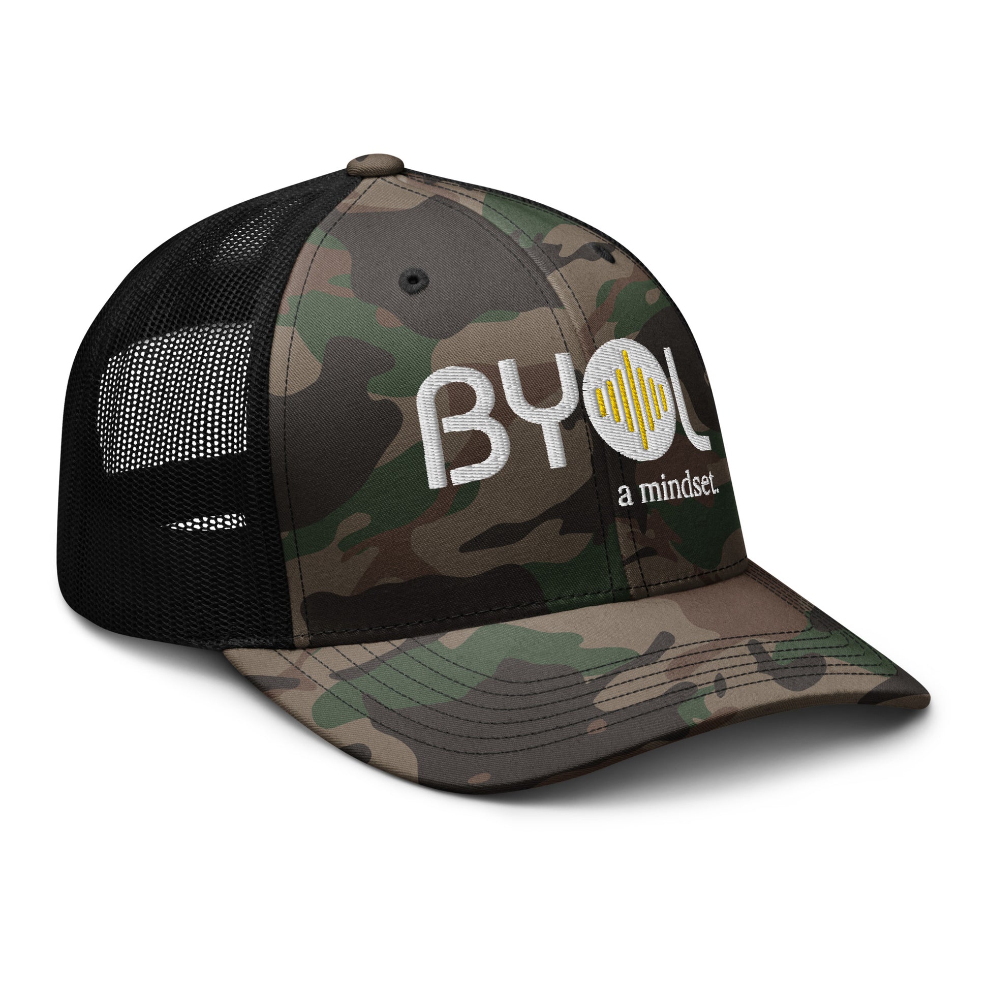 Side of camo/black retro trucker hat with "BYOL a mindset" embroidered on the front in white and yellow, featuring a black mesh back, displayed against a clean background. Available in various colors: black, brown, green, and beige.