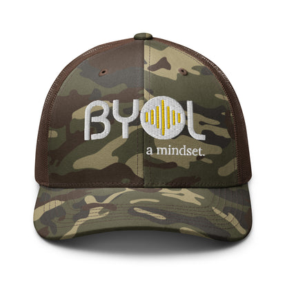 Camo/brown camouflage retro trucker hat with "BYOL a mindset" embroidered on the front in white and yellow, displayed against a clean background. Available in various colors: black, brown, green, and beige.