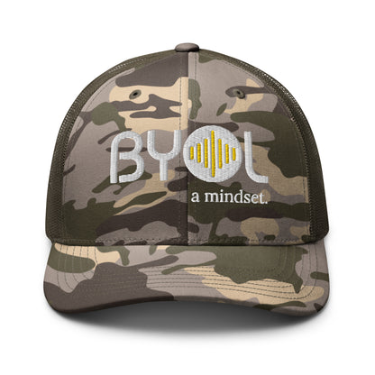 Camo/Olive camouflage retro trucker hat with "BYOL a mindset" embroidered on the front in white and yellow, displayed against a clean background. Available in various colors: black, brown, green, and beige.