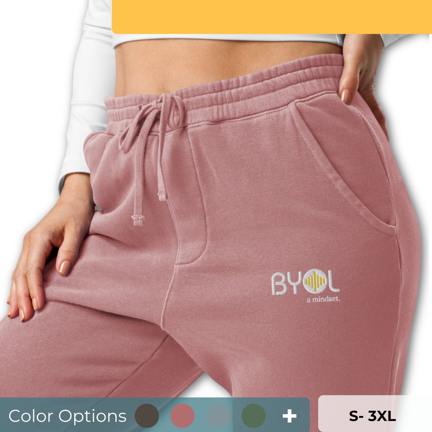 Close-up of a woman wearing pigment pink BYOL mindset joggers with color options in brown, green, pink, and blue, available in sizes S to 3XL.