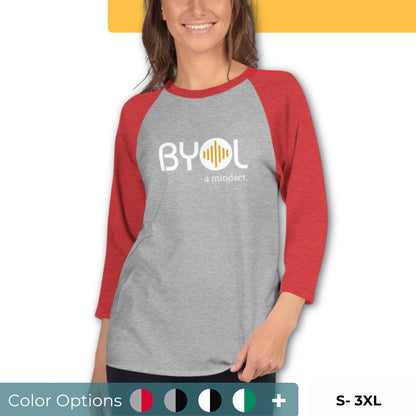 Woman wearing a gray and red BYOL mindset raglan t-shirt with color options in red, gray, black, white, and green, available in sizes S to 3XL.