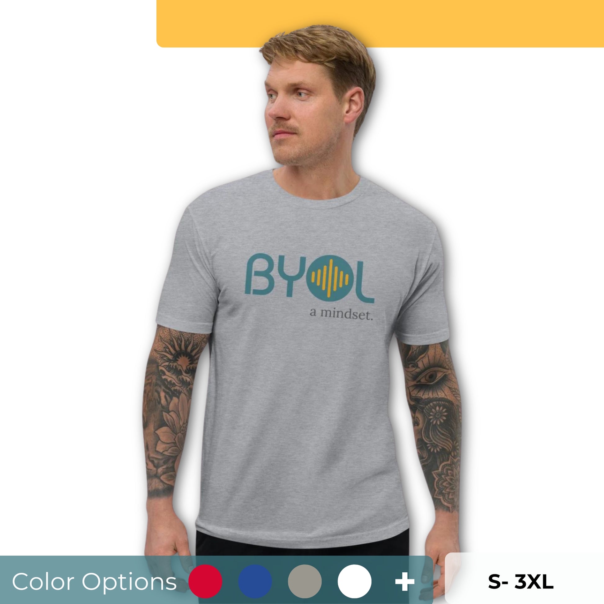 A young man with short blonde hair and arm tattoos wearing a light gray "BYOL: a mindset" T-shirt, standing and looking to the side. The T-shirt features the "BYOL" logo in teal and yellow on the front and is available in multiple colors (red, blue, gray, white, plus more) and sizes (S-3XL). The "be you out loud" logo is displayed at the top.