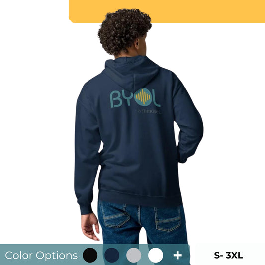 A young man with curly hair wearing a navy blue "BYOL: a mindset" hoodie, viewed from the back. The hoodie features the "BYOL" logo in teal and yellow on the back and is available in multiple colors (black, gray, navy, white, plus more) and sizes (S-3XL). The "be you out loud" logo is displayed at the top.