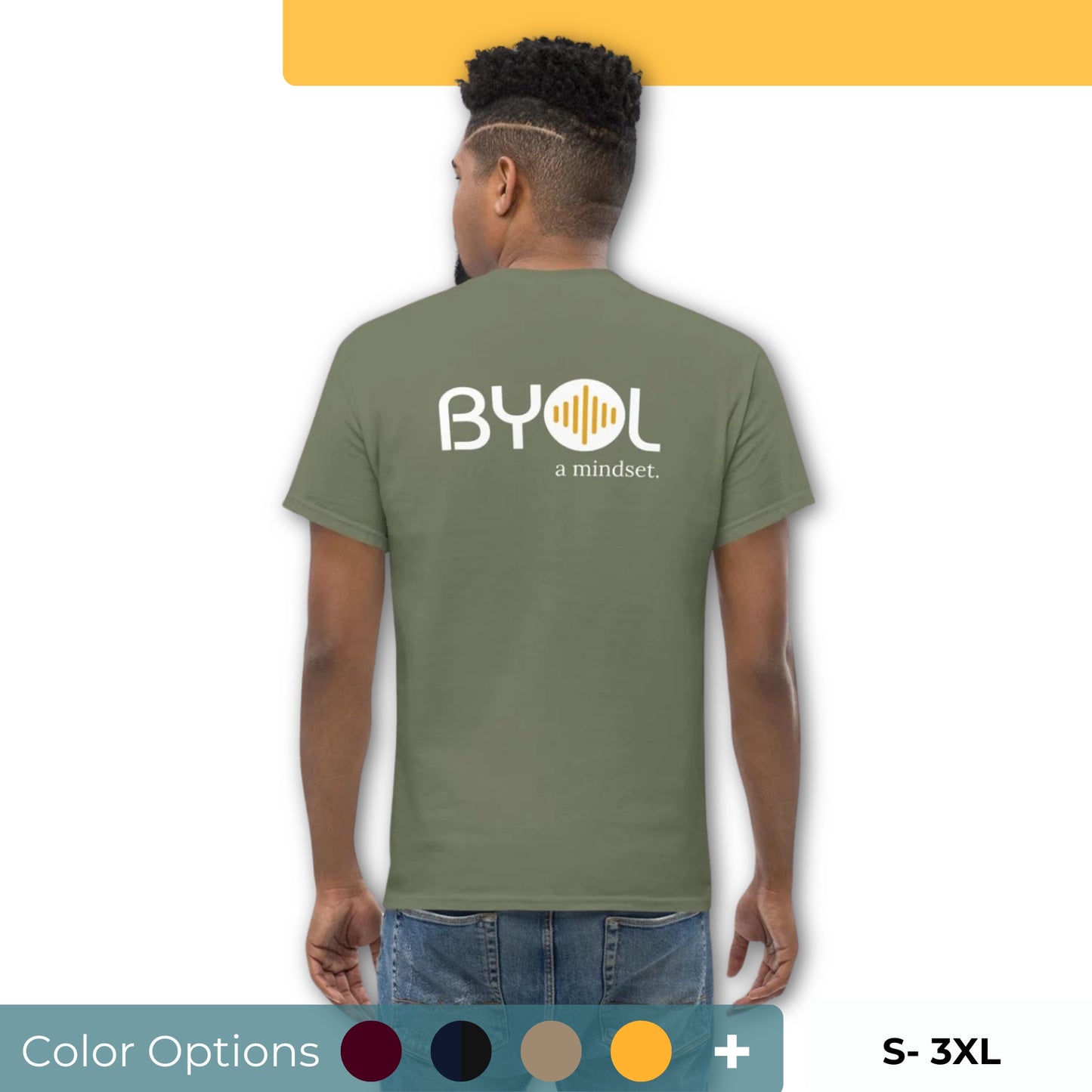 A young man with short curly hair wearing an olive green "BYOL: a mindset" T-shirt, viewed from the back. The T-shirt features the "BYOL" logo in white and yellow on the back and is available in multiple colors (maroon, black, brown, gold, plus more) and sizes (S-3XL). The "be you out loud" logo is displayed at the top.