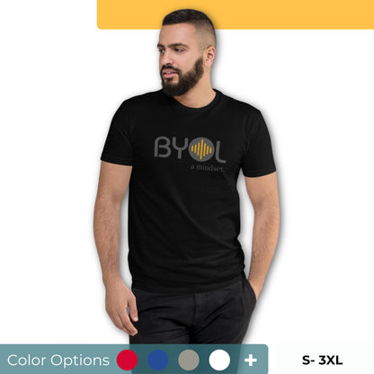 A young man with short dark hair and a beard wearing a black "BYOL: a mindset" T-shirt, standing with one hand in his pocket and looking to the side. The T-shirt features the "BYOL" logo in gray and yellow on the front and is available in multiple colors (red, blue, gray, plus more) and sizes (S-3XL). The "be you out loud" logo is displayed at the top.