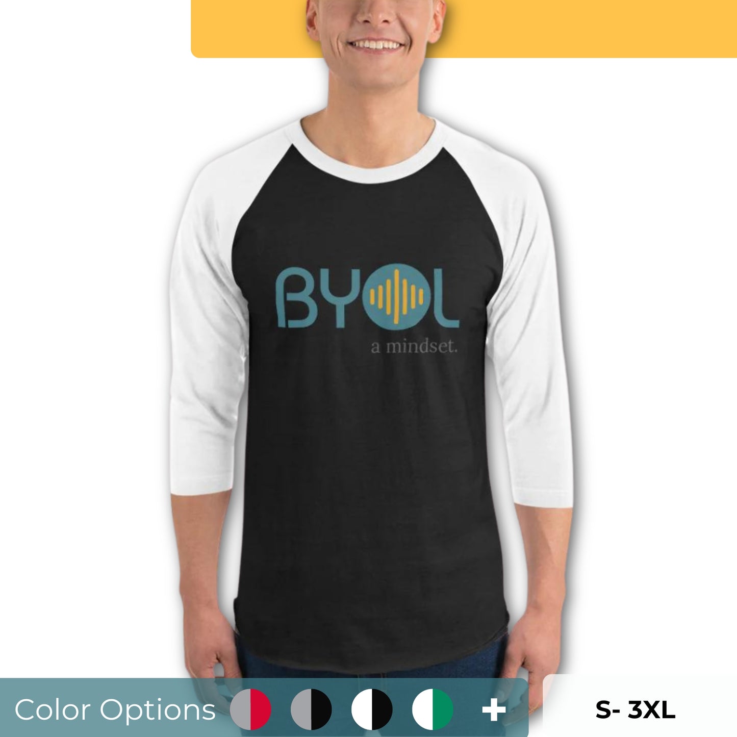 A young man wearing a black and white "BYOL: a mindset" raglan T-shirt with three-quarter sleeves, smiling and standing with his arms at his sides. The T-shirt features the "BYOL" logo in teal and yellow on the front and is available in multiple colors (red, black, white, green, plus more) and sizes (S-3XL). The "be you out loud" logo is displayed at the top.