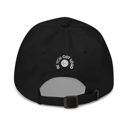 Rear view of a black adjustable baseball cap with white embroidered text 'Be You Out Loud' above the strap.