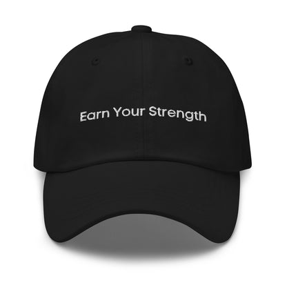 A black dad hat with the phrase "Earn Your Strength" embroidered in white stitching across the front.