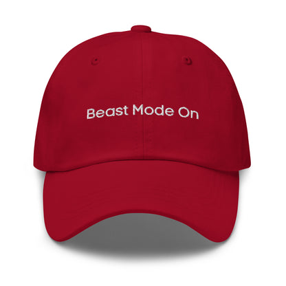 A red dad hat with the phrase "Beast Mode On" embroidered in white stitching across the front.