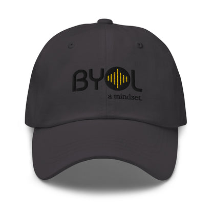 Grey classic dad hat with "BYOL a mindset" embroidered on the front in black and yellow, displayed against a clean background. Available in various colors: black, gray, green, pink, and white.