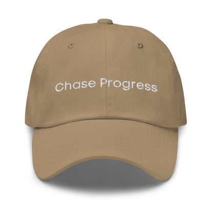 A Khaki dad hat with the phrase "Chase Progress" embroidered in white stitching across the front.