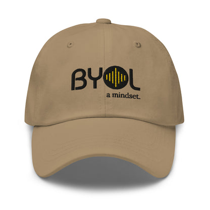 Khaki classic dad hat with "BYOL a mindset" embroidered on the front in black and yellow, displayed against a clean background. Available in various colors: black, gray, green, pink, and white.