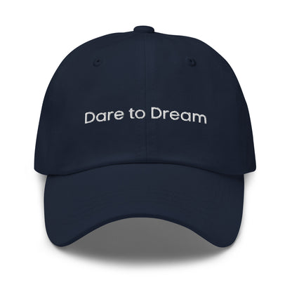 A dark blue dad hat with the phrase "Dare To Dream" embroidered in white stitching across the front.