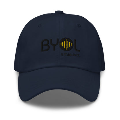 Navy blue classic dad hat with "BYOL a mindset" embroidered on the front in black and yellow, displayed against a clean background. Available in various colors: black, gray, green, pink, and white.