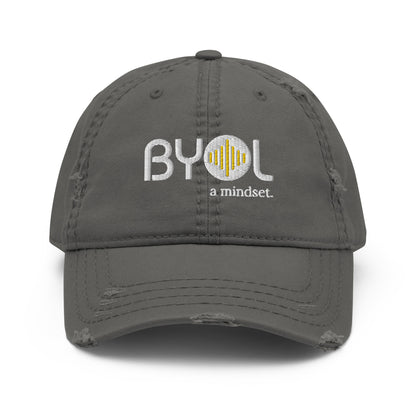 Grey distressed dad hat with "BYOL a mindset" embroidered on the front in white and yellow, displayed against a clean background. Available in various colors: black, navy blue, gray, green, and beige.