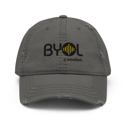 Grey distressed dad hat with "BYOL a mindset" embroidered on the front in black and yellow, displayed against a clean background. Available in various colors: black, navy blue, gray, green, and beige.