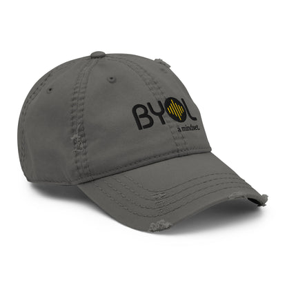 Black distressed dad hat with "BYOL a mindset" embroidered on the front in black and yellow, featuring intentional wear and tear details, displayed against a clean background. Available in various colors: black, navy blue, gray, green, and beige.