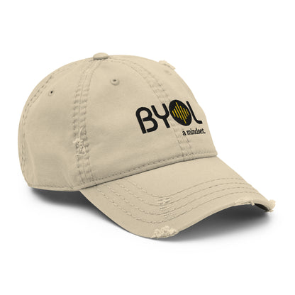 Khaki distressed dad hat with "BYOL a mindset" embroidered on the front in black and yellow, featuring intentional wear and tear details, displayed against a clean background. Available in various colors: black, navy blue, gray, green, and beige.