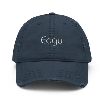 A front view of a blue distressed baseball cap with the word "Edgy" embroidered in white on the front panel, featuring a frayed brim and distressed details for a worn, stylish look.