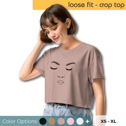 Woman tilting head with closed eyes, wearing a taupe crop top featuring a line art face design, with color options and sizes ranging from XS to XL displayed.