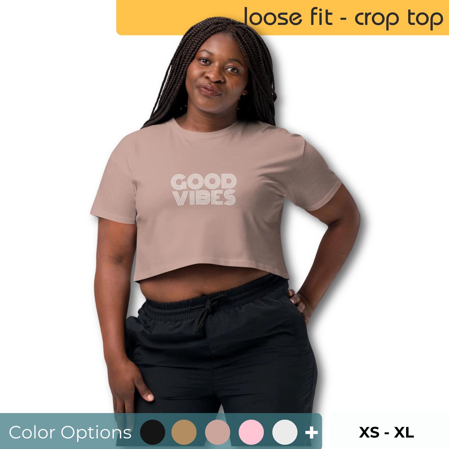 Confident woman modeling a hazy pink loose-fit crop top with 'GOOD VIBES' print, shown with a variety of color swatches and available sizes XS through XL.